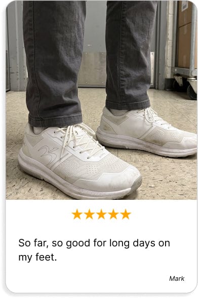 White athletic sneakers with mesh uppers, worn by a person in gray pants, providing comfort for long days on feet.