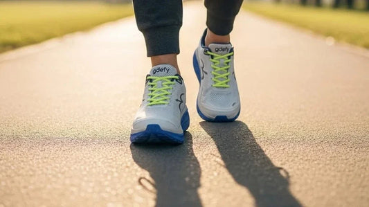 Man walking on a path wearing gray and blue G-Defy Mighty Walk shoes with VersoShock technology