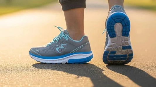 Gray-blue Mighty Walk athletic walking shoes with cushioned VersoShock midsole mid-stride on a sunlit path, feet-level view of the heel