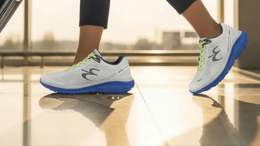 Traveler walking through a sunlit airport concourse with a rolling suitcase, wearing G-Defy Mighty Walk comfort shoes