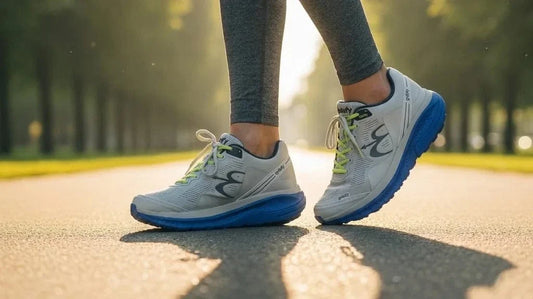 Gray and blue G-Defy Mighty Walk walking shoes mid-stride on a sunlit tree-lined park path