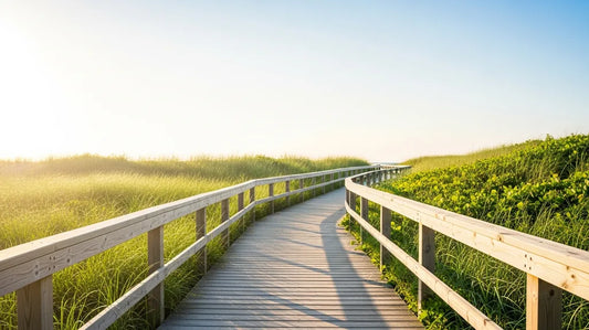 Sunlit wooden boardwalk through green coastal grasses on a warm summer day — comfortable summer sandals season