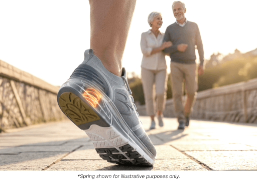 Grey athletic shoe with a visible orange spring cushion in the heel, worn by a person walking outdoors. An older couple strol