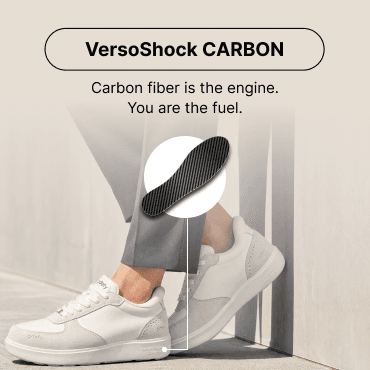 White casual sneakers with VersoShock CARBON insoles, worn by a person in grey pants, highlighting the carbon fiber pattern.