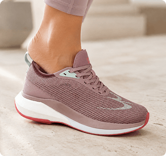 Dusty rose mesh running shoe with a thick white and red sole, worn on a foot with light purple leggings.