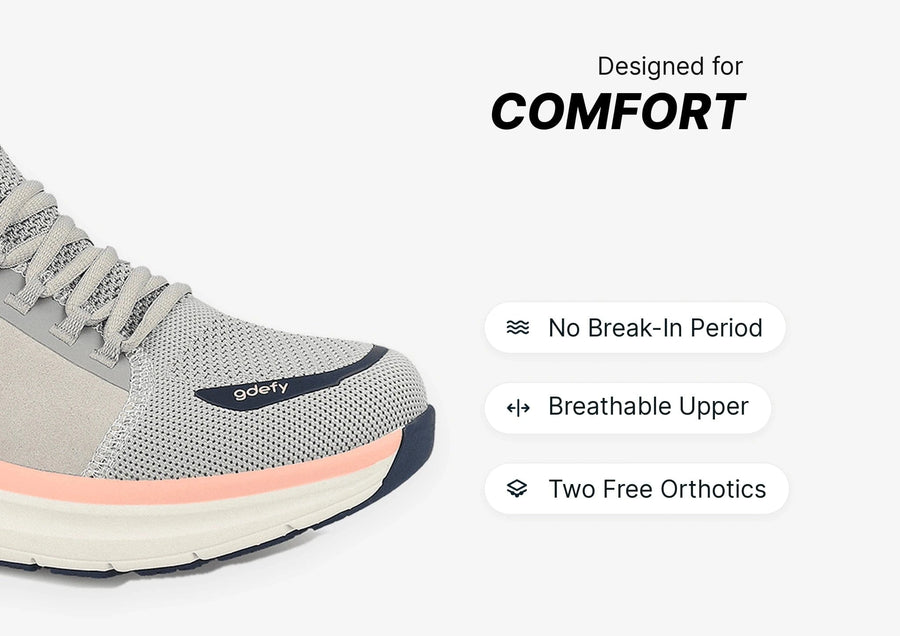 Light gray GDEFY running shoe with breathable mesh upper, peach midsole stripe, and dark blue outsole, designed for comfort.