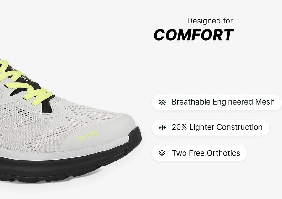 Light grey athletic shoe with neon yellow laces and a black sole, featuring breathable mesh for enhanced comfort.