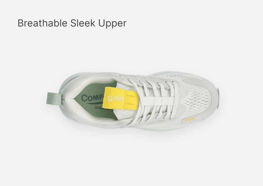 Light grey running shoe with a breathable mesh upper, white laces, and a yellow gdefy tongue tag, top-down view.